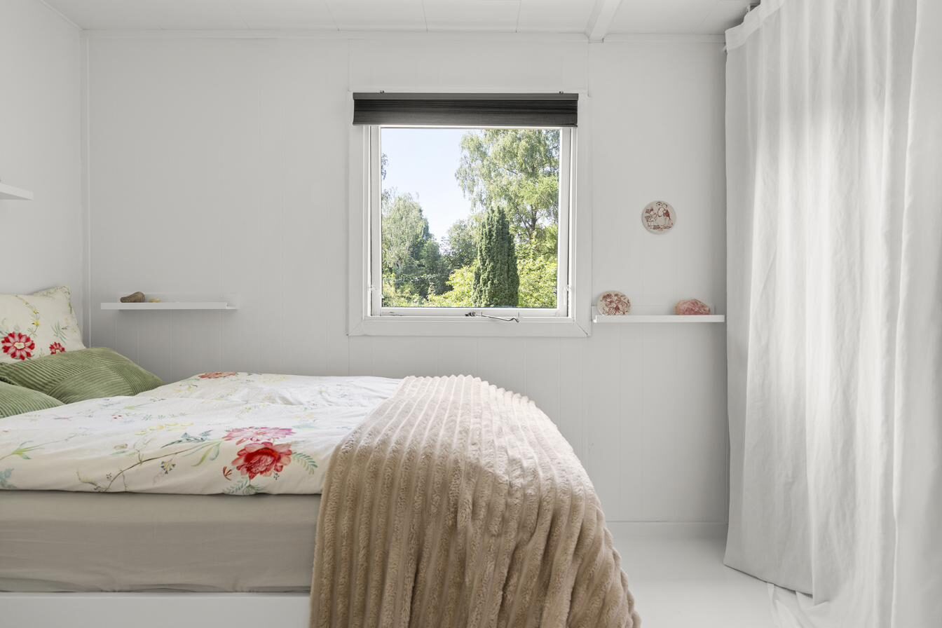 Soveværelse med blomstret sengetøj og haveudsigt – sommerhus til salg Nordsjælland